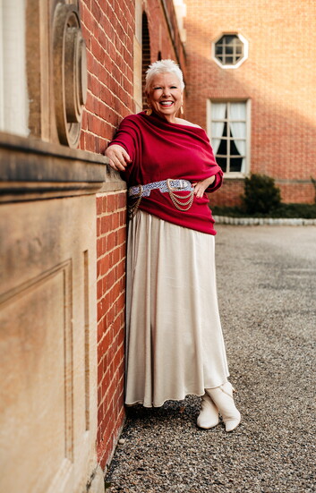 A glamorous off-the-shoulder sweater in burgundy matches the graceful drape of a champagne satin skirt, cinched with a black-and-white leopard print belt.