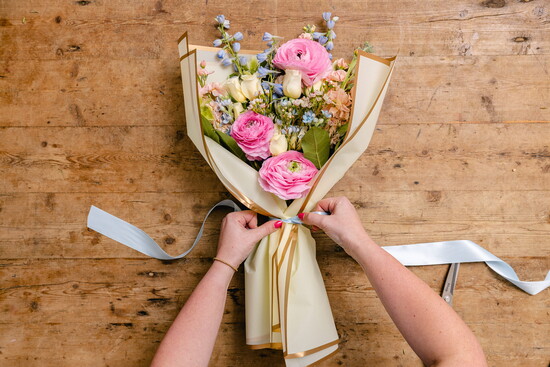 Cinch the paper over the stems, below the flowers. This wrapping style keeps the flower petals protected and on display!  Tie a bow with a coordinating r