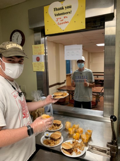 Homeless Solutions Inc. volunteers serve dinner to a shelter guest