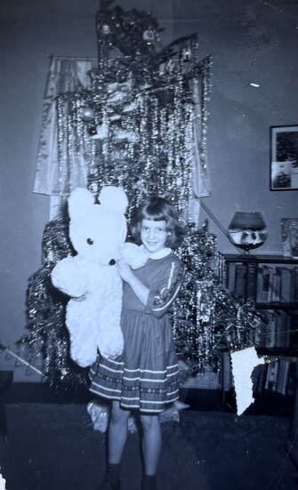 Mayor Kelly Burk at age five, beaming with her enormous white teddy bear from Santa. A timeless Christmas memory!