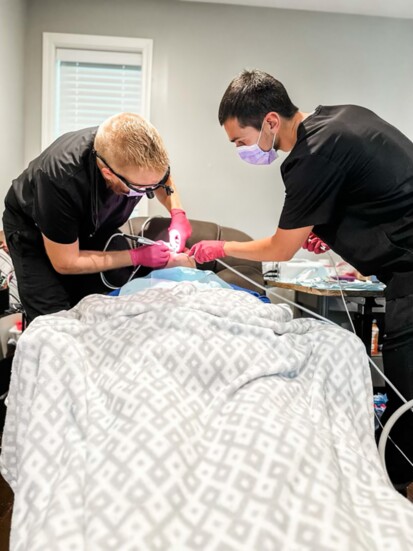 Dr. Sky Kurlbaum and team member operate on a woman's teeth in her home 