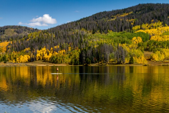 Paddle boarding on a quiet alpine lake in fall.