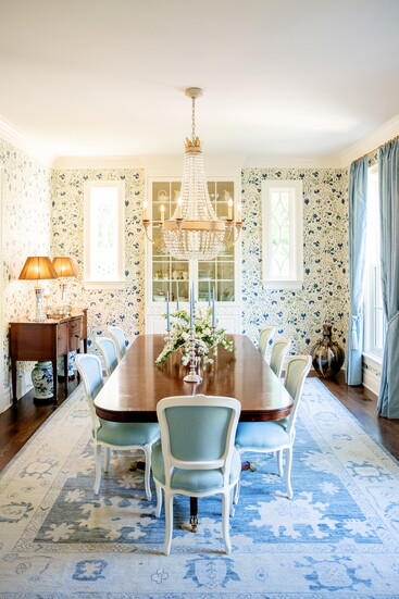 The dining room walls are swathed in Soane Dianthus Chintz wallpaper, illuminated by a Visual Comfort crystal chandelier