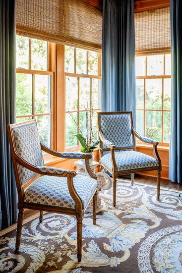 Knotty pine paneling creates a warm and cozy atmosphere in the study, where an antique Aubusson rug from the homeowner’s family accents the floor. 