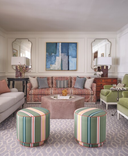 The living room features a lovely mix of shapes and colors – like the hexagon-shaped Highland House ottoman in gunmetal gray leather – as well as new and 