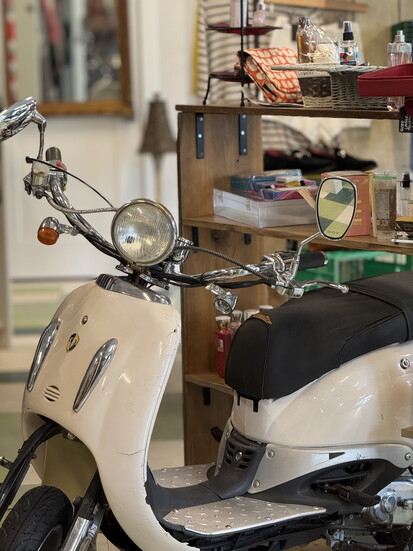 A moped at the thrift store represents the various forms of transport kids use, such as skateboards and bikes.