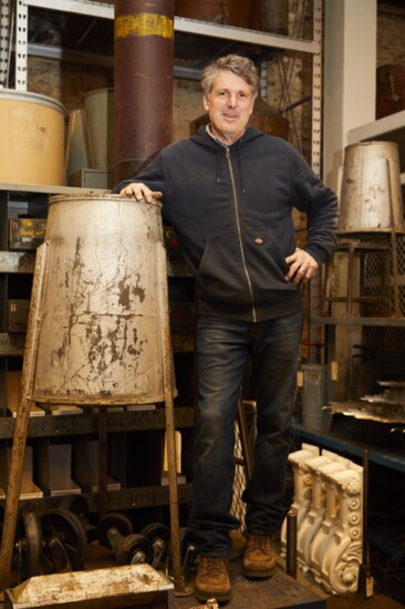 John Hiden, owner of Monger’s Market feeling grateful as he stands on an Industrial Worktable with large Victorian Corbels in the background. 