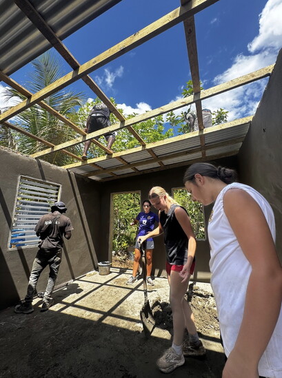 Adri Marble, Kennedy Smith, and Trinity Krause working with locals to complete concrete work and attach the roof.