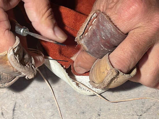 Hand sewing moccasins one stitch at a time.