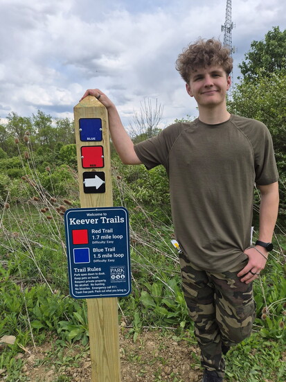 Eagle Scout Dustin Minick with one of the new trail markers he installed. Photo provided by the Warren County Park District. 
