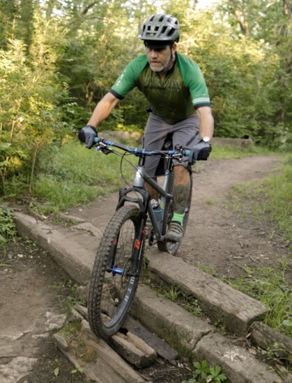 Adam Elwell maneuvers over an obstacle on the trail, which can make mountain biking more challenging. 