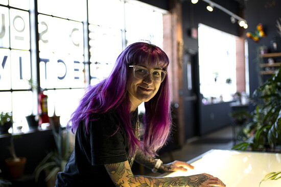 Miranda Chisholm, tattoo artist, works on a lighted table to design a custom tattoo for a client.
