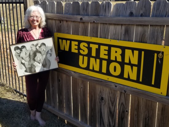 Carla Rabon poses by a Western Union sign in her OKC backyard, while holding a photo of The Five Americans, which included her late husband Mike Rabon.