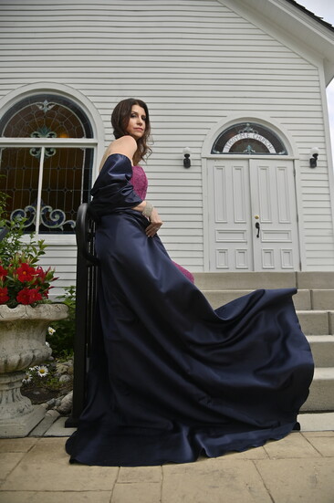 On Bethany: Purple Lace Dress features structured corset boning and a draped sash detail.