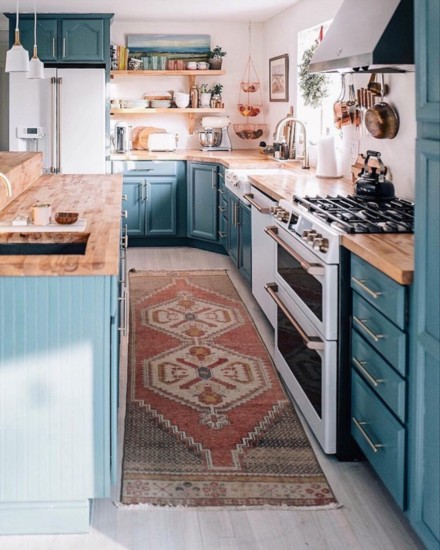 This kitchen flaunts blue tones in cabinetry with contrasting dusty reds and natural wooden countertops; @jessannkirby
