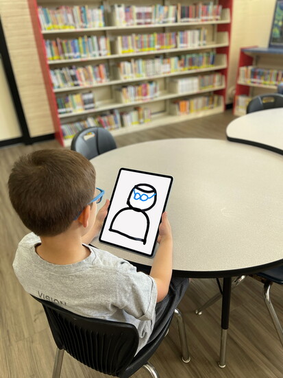 Joey Hintz recreates the Vision Nonprofit logo, complete with his signature blue glasses, on his tablet. 