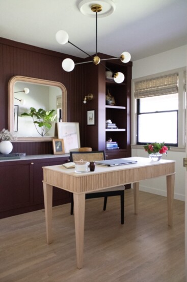 Home office with bold burgundy cabinetry, beadboard paneling and brass hardware and sconces bring a touch of luxury.  (Photo by Katie Broden)