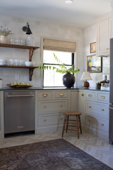 Mushroom-hued cabinets paired with Zellige-inspired tiles with classic wainscoting and brass accents. (Photo by Katie Broden)