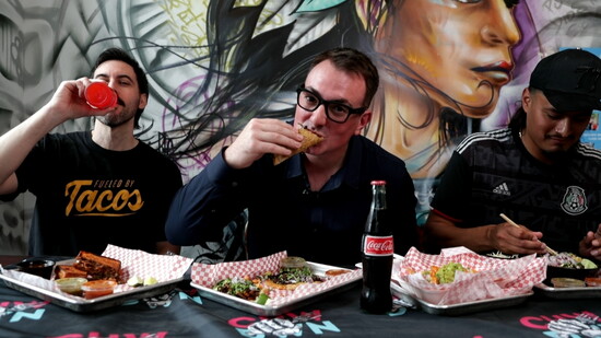 Nathan Taylor, President/CEO of Chowdown Cincinnati (center), chows down on a taco from a local restaurant.