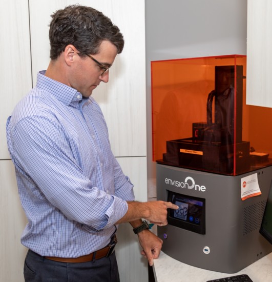 Dr. Clay Fulks operates a 3D printer that is creating a teeth mold.