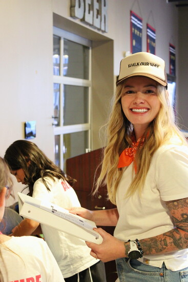 WOW's Board Member, Dani Vanderpool smiles big as she helps youth volunteers carefully pack new backpacks for NOCO students in need.