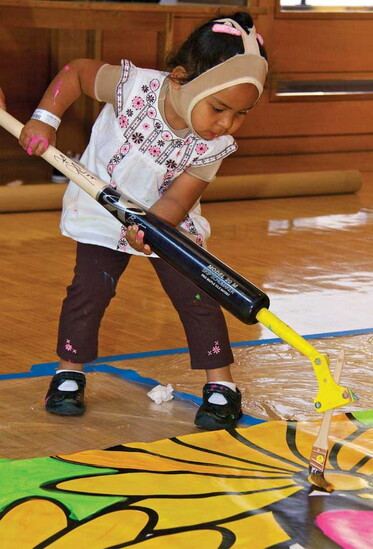Painting with a brush crafted from a retrofitted baseball bat. Photography by Portraits of Hope.