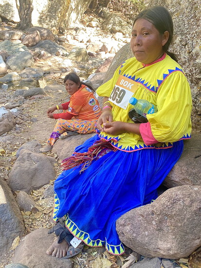 A Rarámuri woman, her foot wrapped, sitting on a rock—she found the strength to continue.