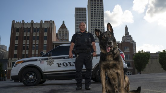 Sworn to protect and serve, Officer Chad Murtaugh and K9 Riggs stand ready in front of Tulsa's skyline.
