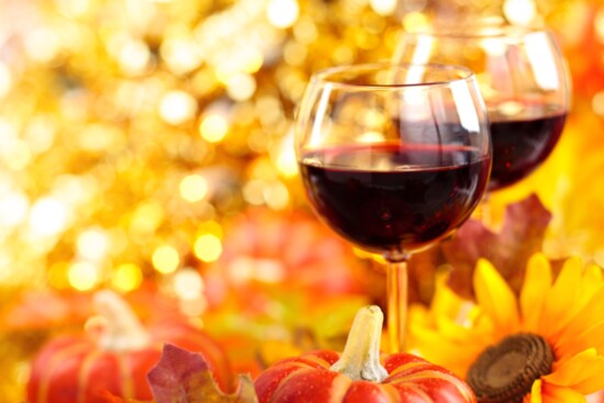 Glasses of red wine among flowers and foliage.