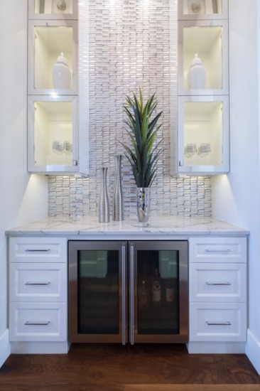 The wine bar features shimmering reflective tile as the backdrop with lighted side cabinets for glasses. The perfect spot for entertaining guests.