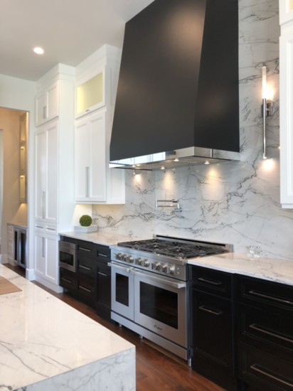 Nicole selected a single slab of quartzite stone for the backdrop behind her range , topped with a modern classic hood trimmed in chrome.
