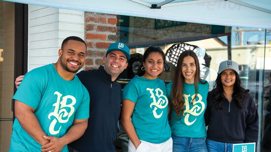 Long Beach Coast team members greet fans with smiles at their table during a fan event.