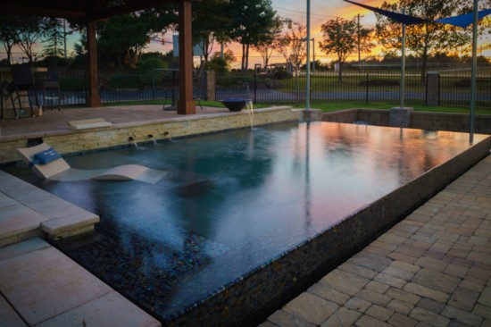 Linear pool with perimeter overflow and negative edge complements the all-tile tanning ledge in this sleek, modern design.