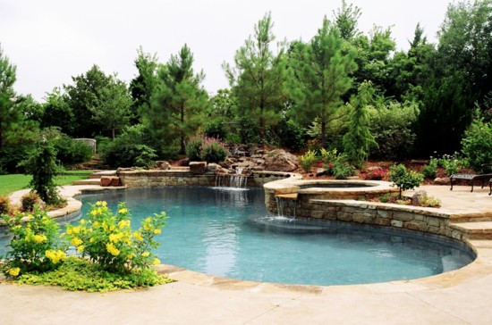 Freeform, natural with a rock waterfall flowing to pool. This design features a round spa and a raised wall on back side. 