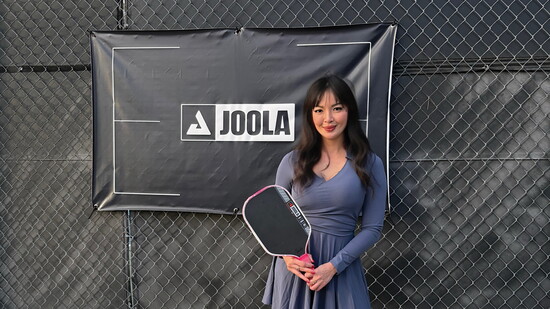 She poses with her pickleball paddle on the court.