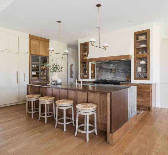 The open concept kitchen features elegant lighting, high-end appliances, glass cabinets and a striking quartzite countertops.