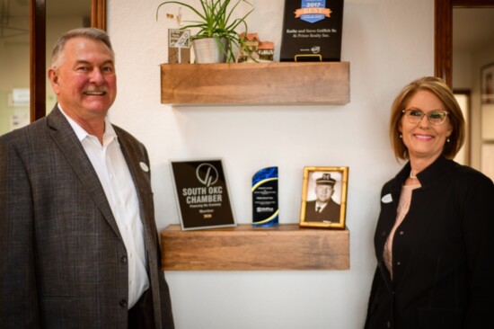 The Griffiths pose alongside a photo of Kathy's father, Norman Nelson Bewley, who opened Prime Realty with his wife, Rose Ann, in 1990.
