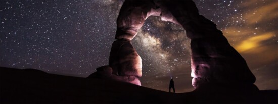 Person Standing Under A Rock Formation On A Starry Night