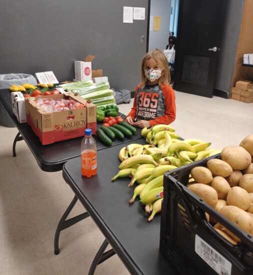 Liam Davies, 6, helps out in the produce section of a recent Mutual Aid Fair. (Photo by Lindsey Davies)