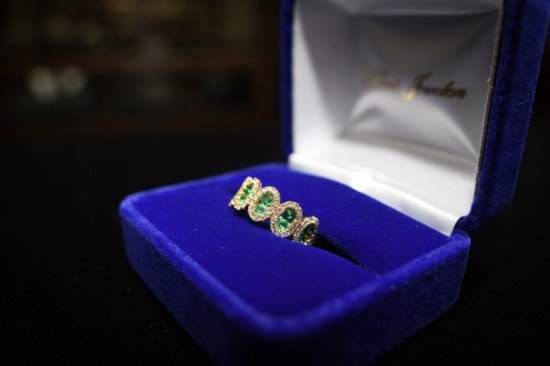 14 karat yellow gold oval halo ladies’ fashion ring set with 12 round cut emeralds and 84 round brilliant cut diamonds. Retail price: $4,200