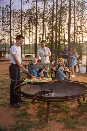 The Fisher and Wieser family grilling by the pond on the grounds of Das Peach haus