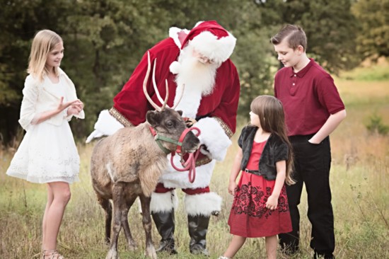 Santa shows off one his reindeers to a few children who are on his nice list.