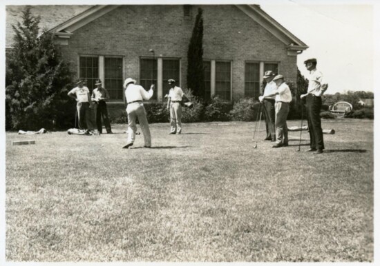 a group of men teeing off in front of the Municipal Golf course club house in 1940.