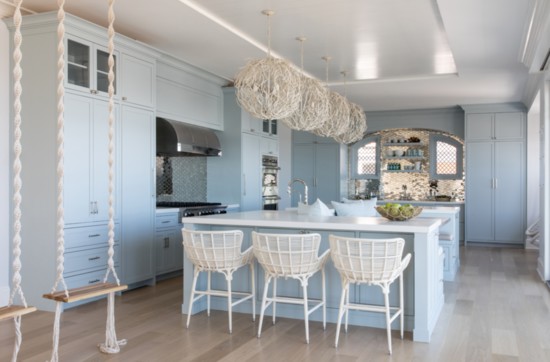 The oversized statement lighting in the kitchen can be seen through the window when looking into the home from the beach for an ethereal effect.