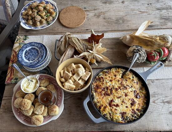 A table scape of flaky layers of buttermilk biscuits, overnight slow cooker apple butter, biscuit crackers, Sausage Balls and Bacon Spinach Artichoke Dip