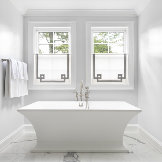 The matte-finished sculptural tub is a work of art. Clean-lined café curtains — with tailored custom-appliqued trim — create privacy while allowing natural ligh