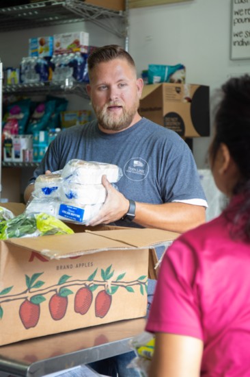 Ryan Allnutt of Thin Line Home Inspections sorts through packaged breads for distribution to families in need through NourishNow, a nonprofit food bank.