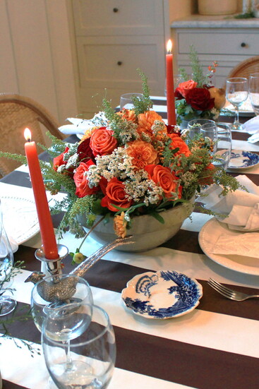 This table arrangement features flowers we foraged, along with garden roses. The crock, blue plate and the pheasant candlesticks were thrifted.