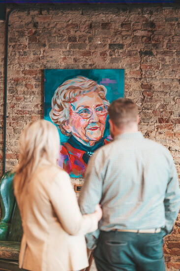 Rob and Emily McDaniel, admiring a painting of Rob's grandmother, Helen