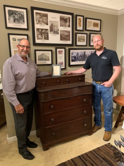 Chad Leopold and Mark Lutz stand next to a chest that Henry Leopold made in 1859.